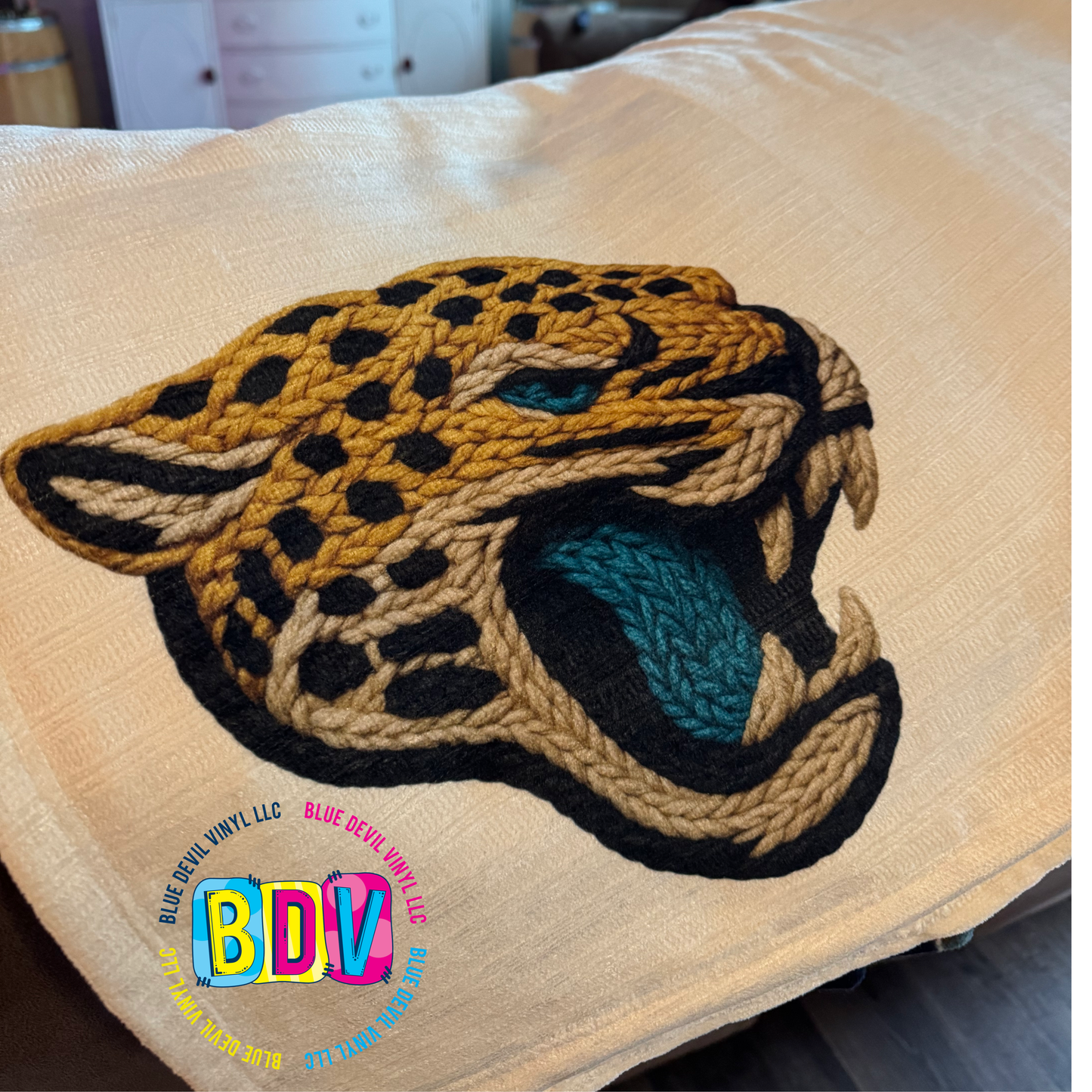 Faux Embroidered Sublimated Design on a beige blanket.