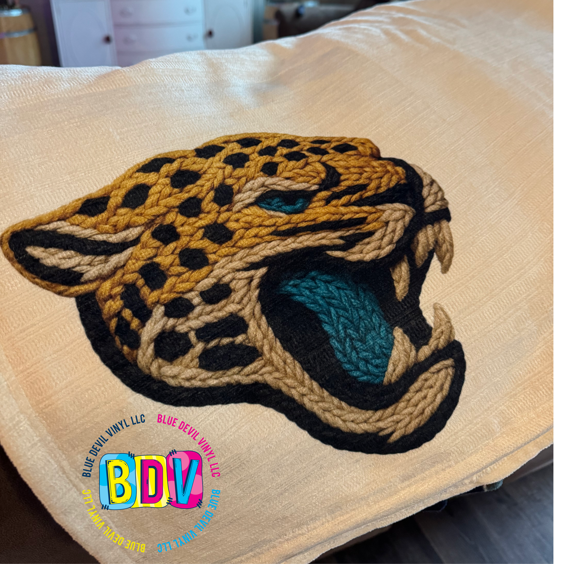 Faux Embroidered Sublimated Design on a beige blanket.