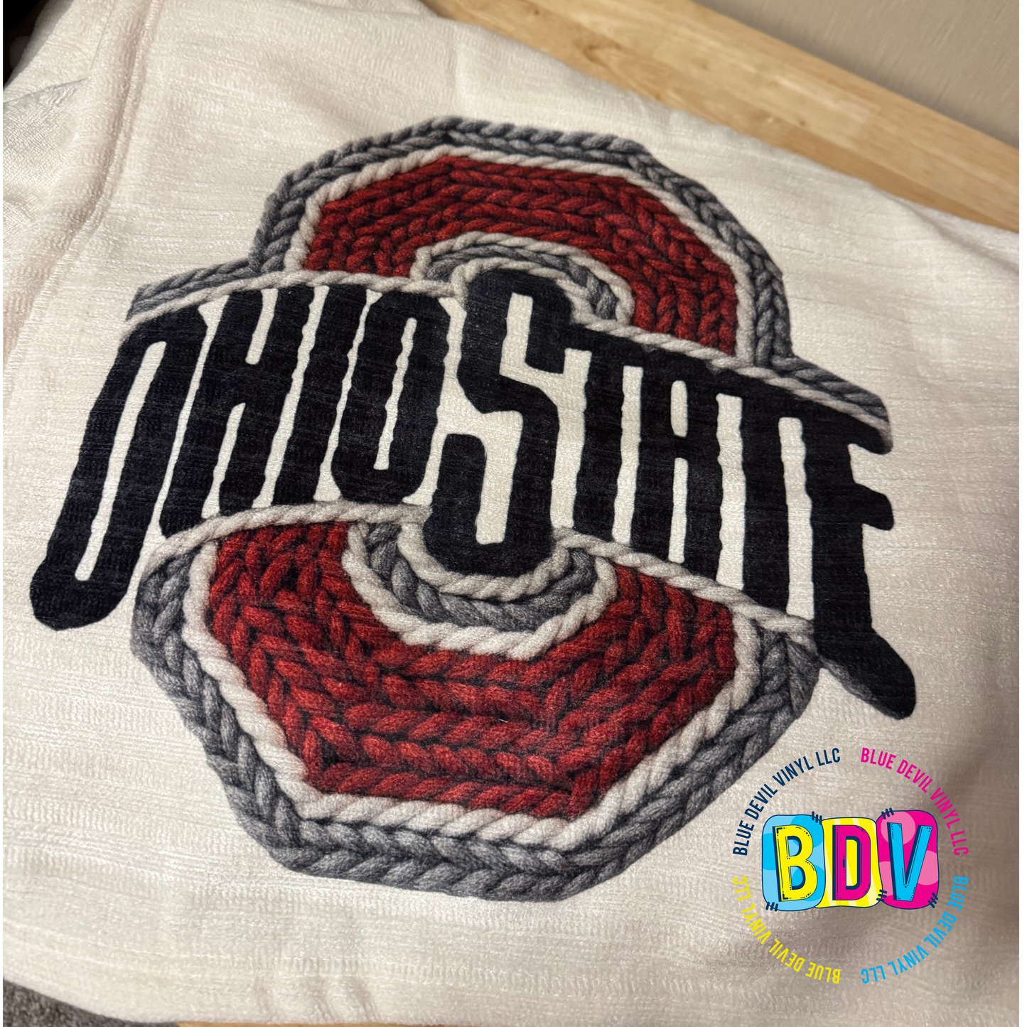 Faux Embroidered Sublimated Design on a beige blanket.